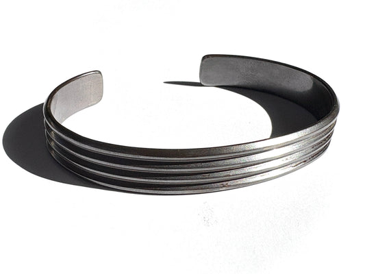 A sterling silver cuff bracelet with a bold, linear pattern, completely oxidized, displayed against a white background.
